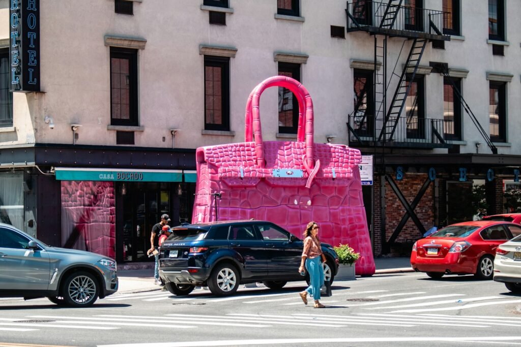 A woman crossing the street in front of a pink bag